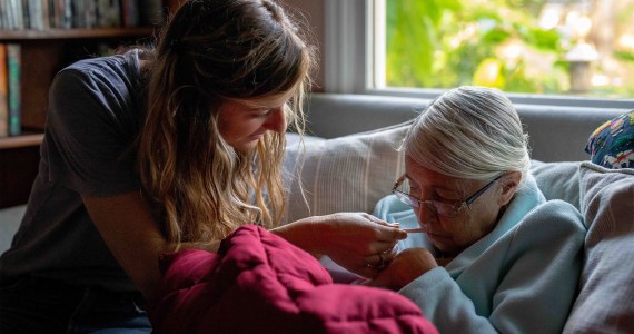 A photo of a caretaker aiding an elderly woman.